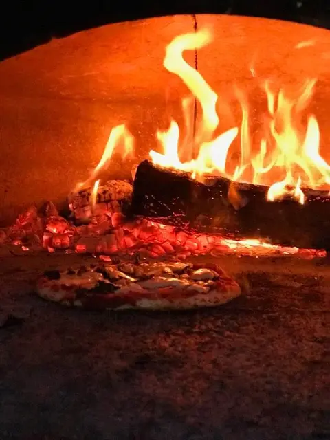 Pizza baking in the wood fire oven